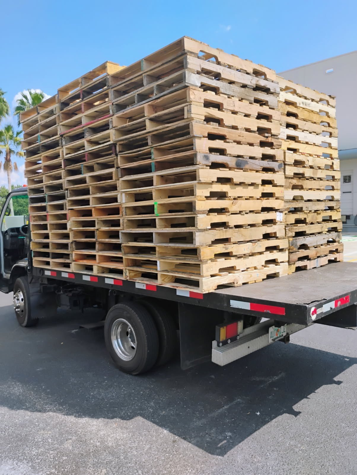 Flatbed truck loaded with stacked wooden pallets